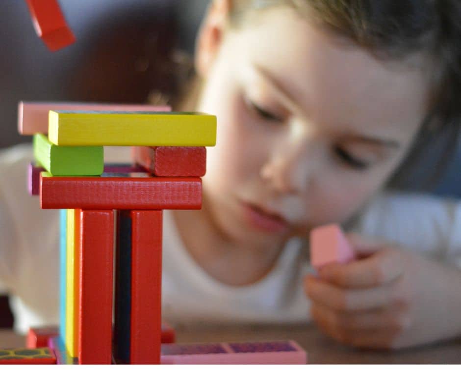 ילדה בת 4 בערך בונה מגדל מקוביות צבעוניות